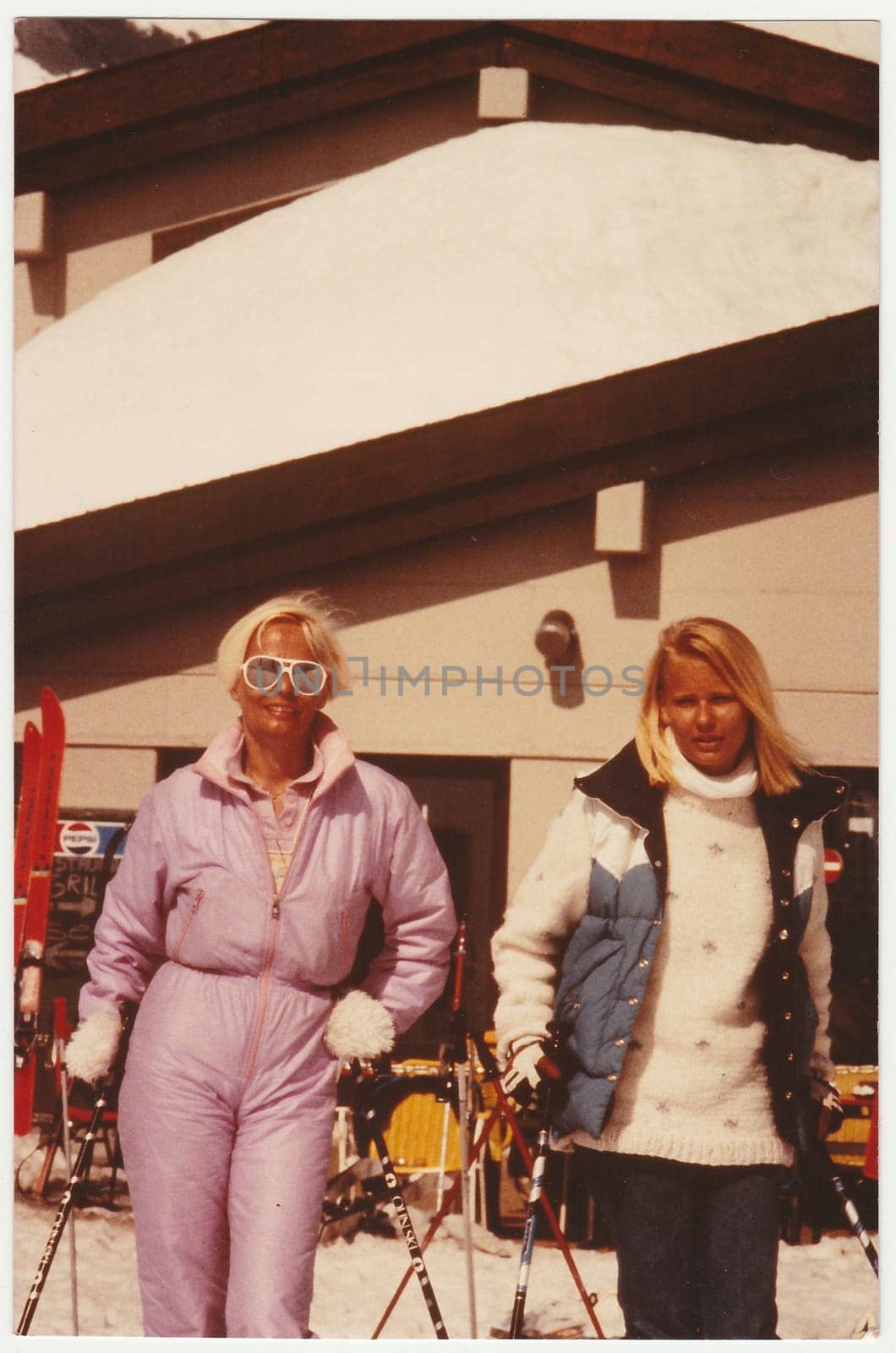 THE ALPS, SWITZERLAND - 1982: Vintage photo shows mother and daughter on winter vacation at the ski resort.