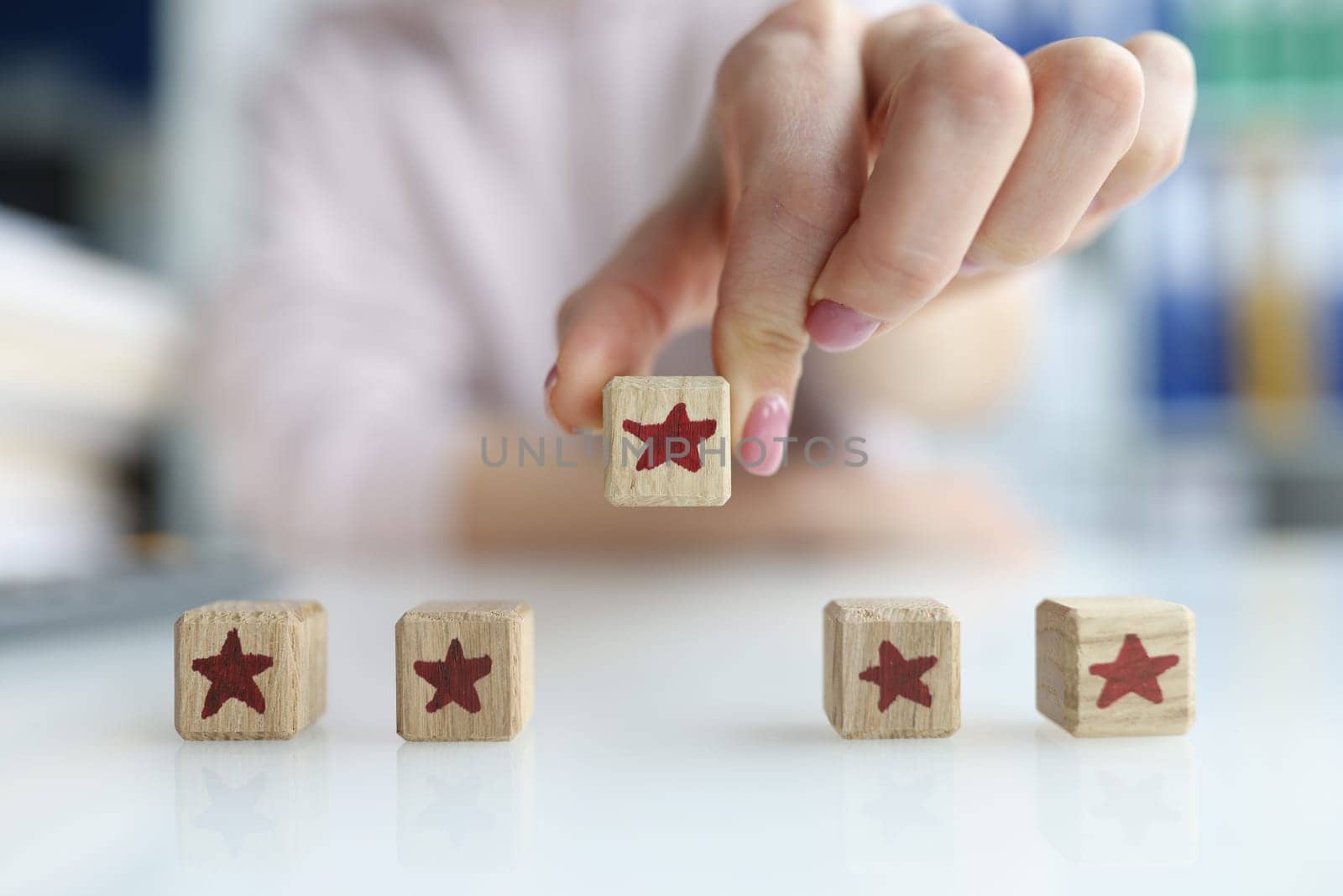 Hand holds cube made of wooden blocks in shape of five red stars. Best concept of customer experience evaluation