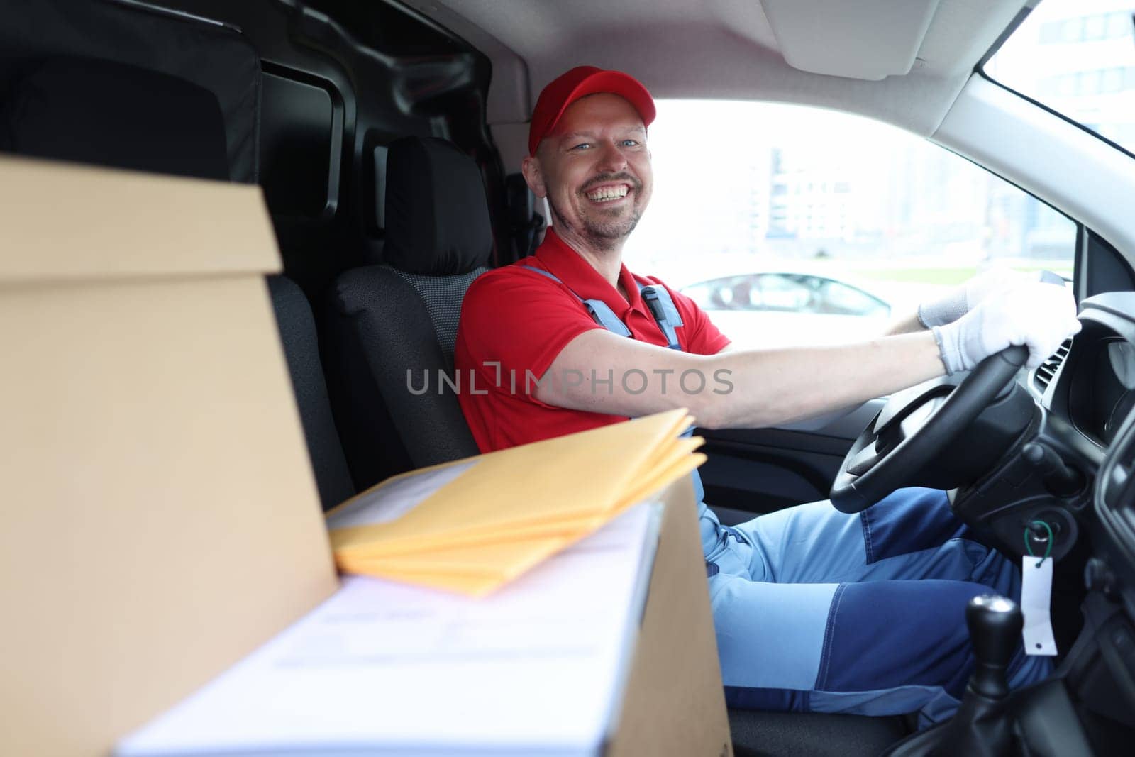 Smiling courier sits in car as driver. Logistics and delivery of goods concept