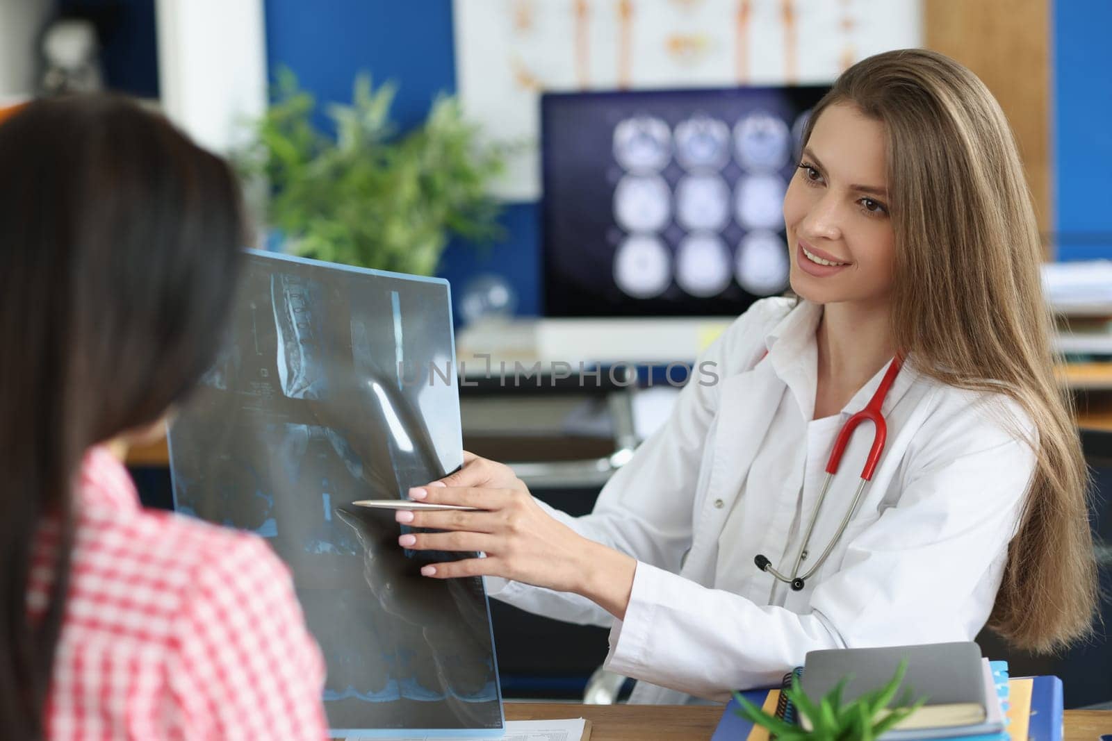 Female patient and doctor with spine x-ray scan meet in hospital. Injury and pain in spines diagnosis and treatment concept
