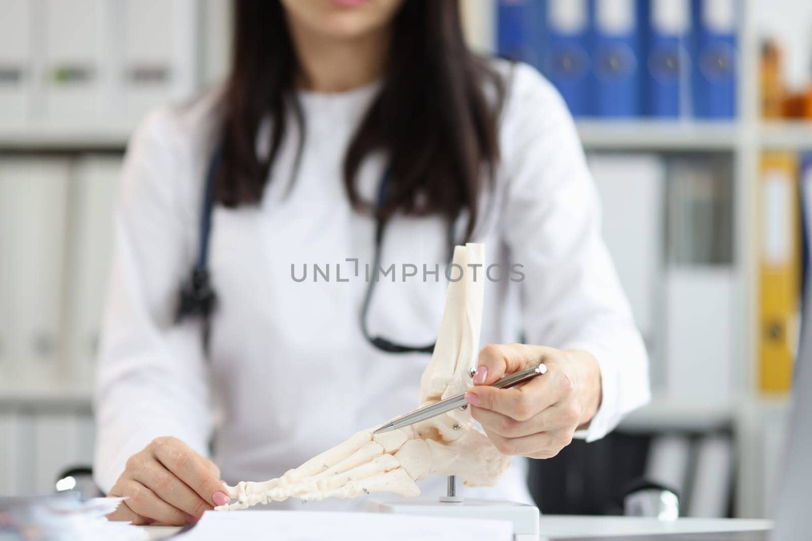 Orthopedic doctor explains physiology of bone model by pointing to point of model. Tell patient how to treat bone disease