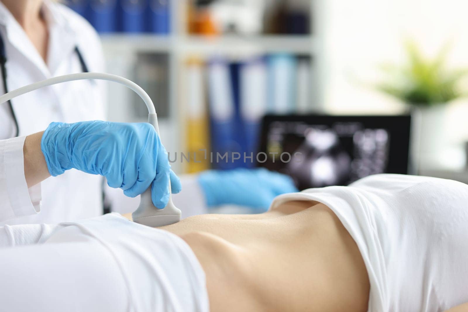 Sonographer technician holds ultrasound probe to diagnose condition of pregnant woman looking at woman uterus on computer screen. Ultrasound of uterus and female reproductive system concept