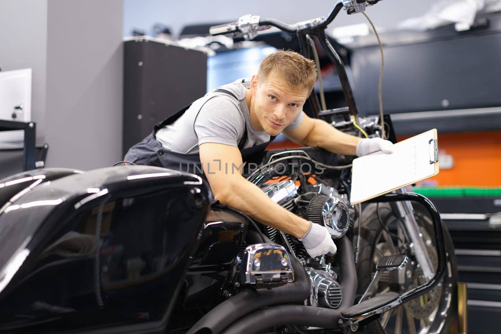 Male mechanic diagnoses modern motorcycle in service center. Concept of vehicle maintenance and transport insurance