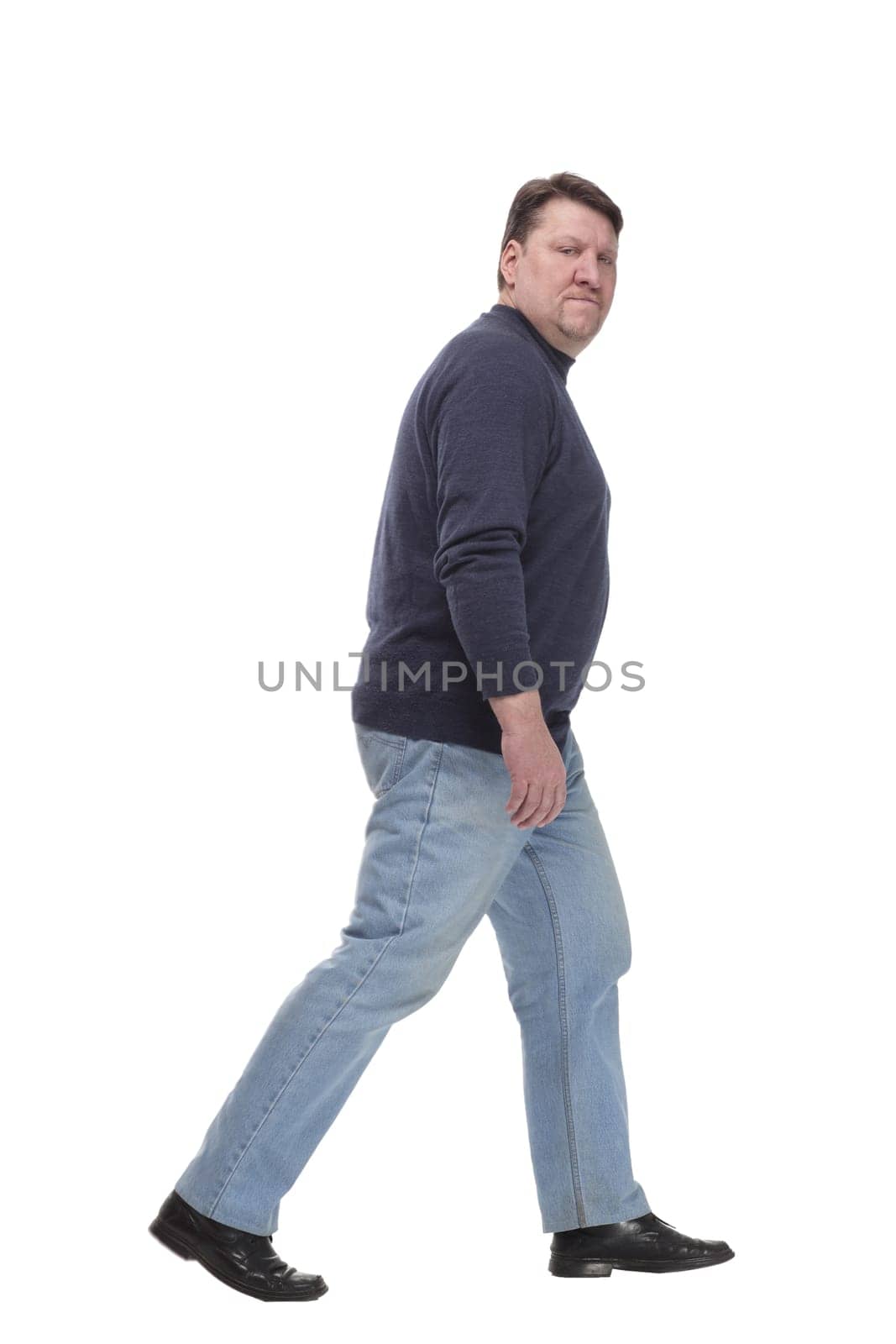 in full growth. Mature man in jeans striding forward.isolated on a white background.