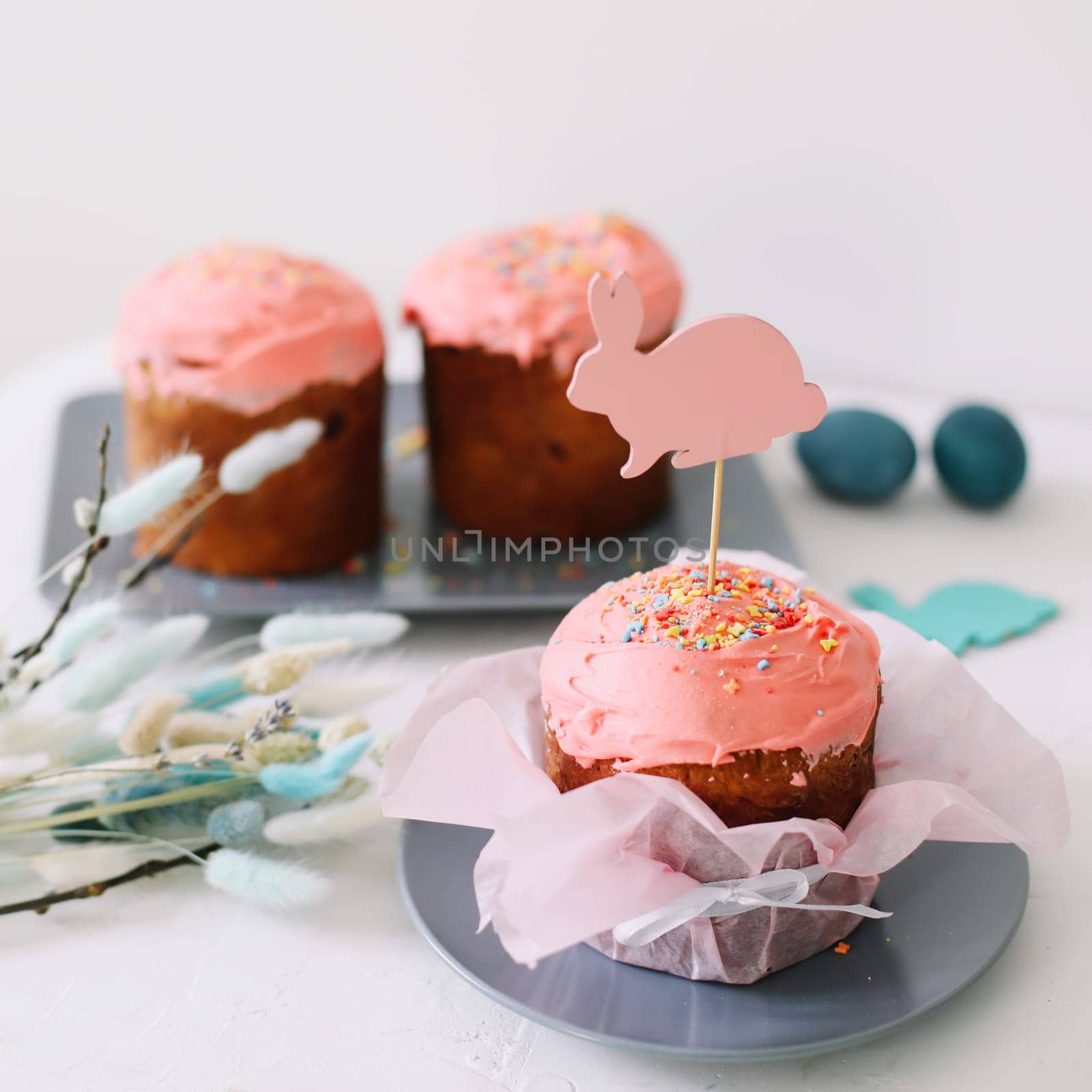 Plate with tasty Easter cake, eggs and willow branches on dark background. High quality photo