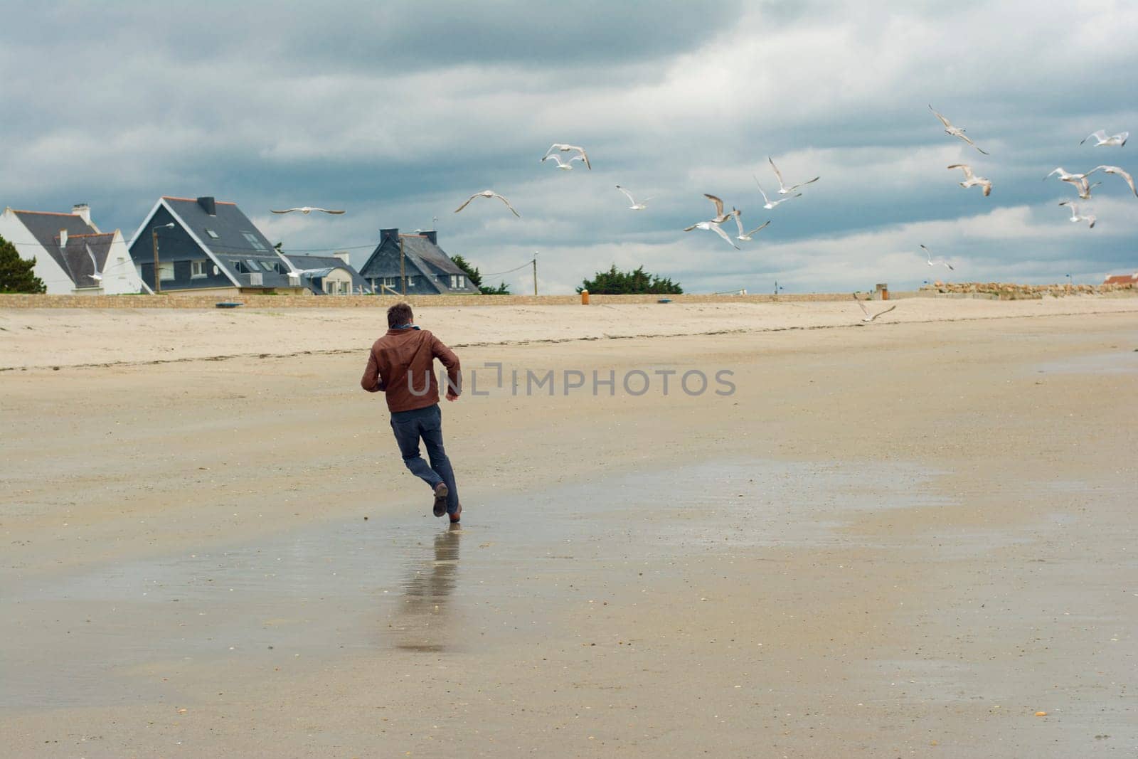 The man runs away and group of seagull birds near