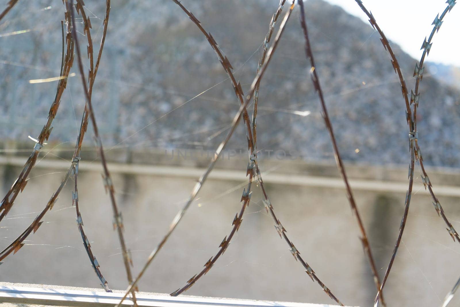 Barbered wire over blue sky and on building ground, rusty