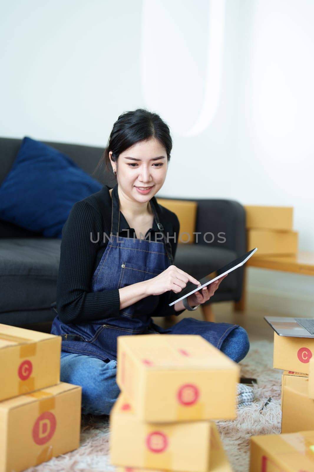 Startup small business entrepreneur of freelance Asian woman smiling and using tablet computer with Cheerful success of item online marketing packaging box and delivery SME idea concept.