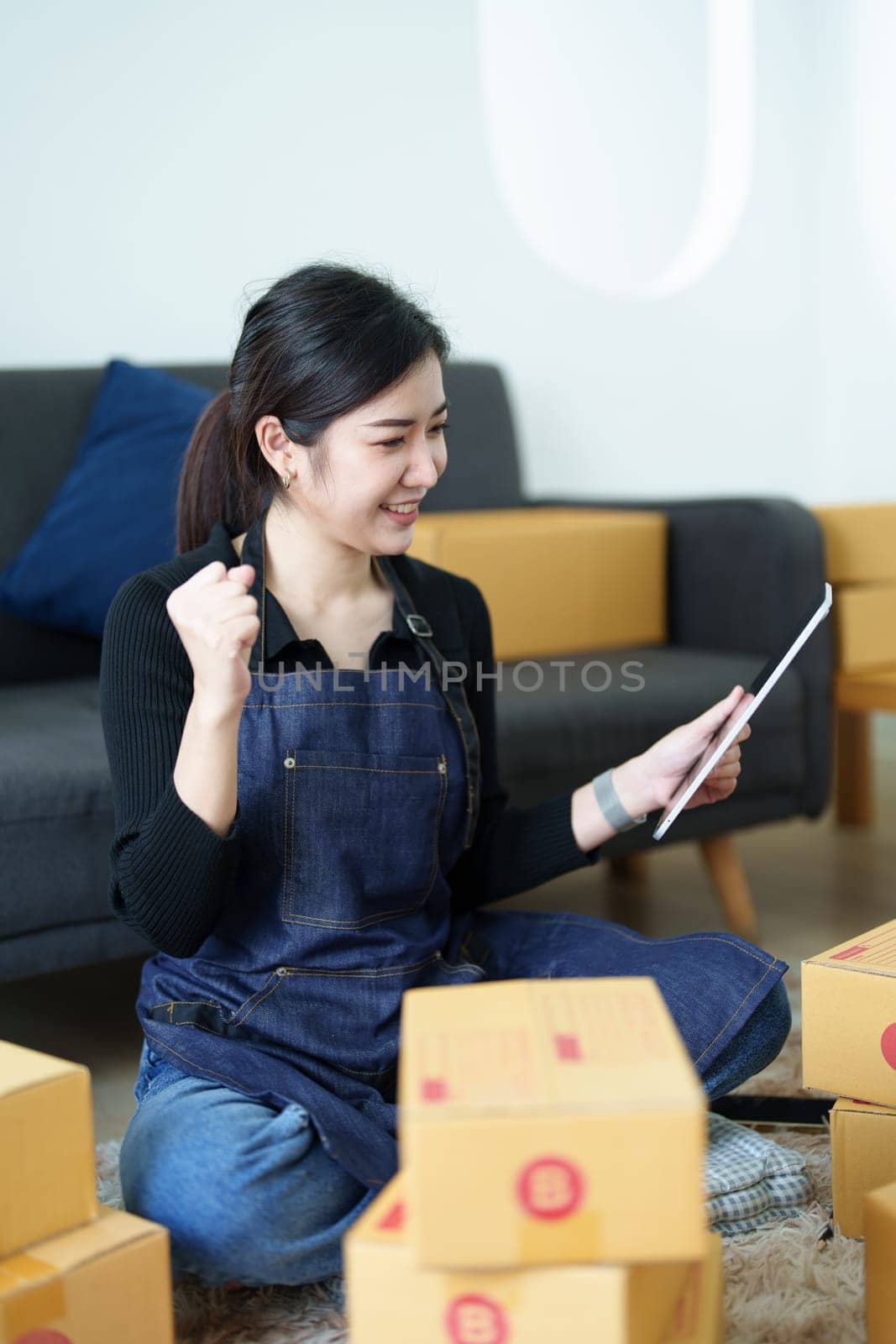 Startup small business entrepreneur of freelance Asian woman smiling and using tablet computer with Cheerful success of item online marketing packaging box and delivery SME idea concept.