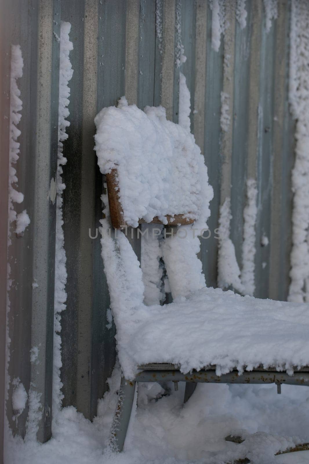 A wooden and metal chair covered in snow by Granchinho