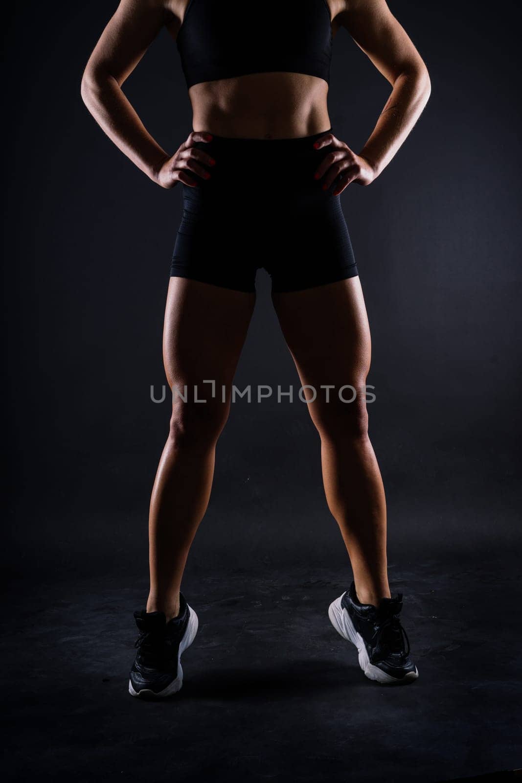 Shaped female legs in sneakers sculpted muscles, dark background