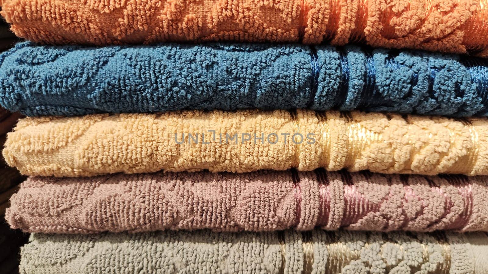 Abstract background and texture from a stack of colored soft terry towels. Lots of colorful bath towels stacked on each other. Cotton towels for hotels, home, bathroom, kitchen by keleny