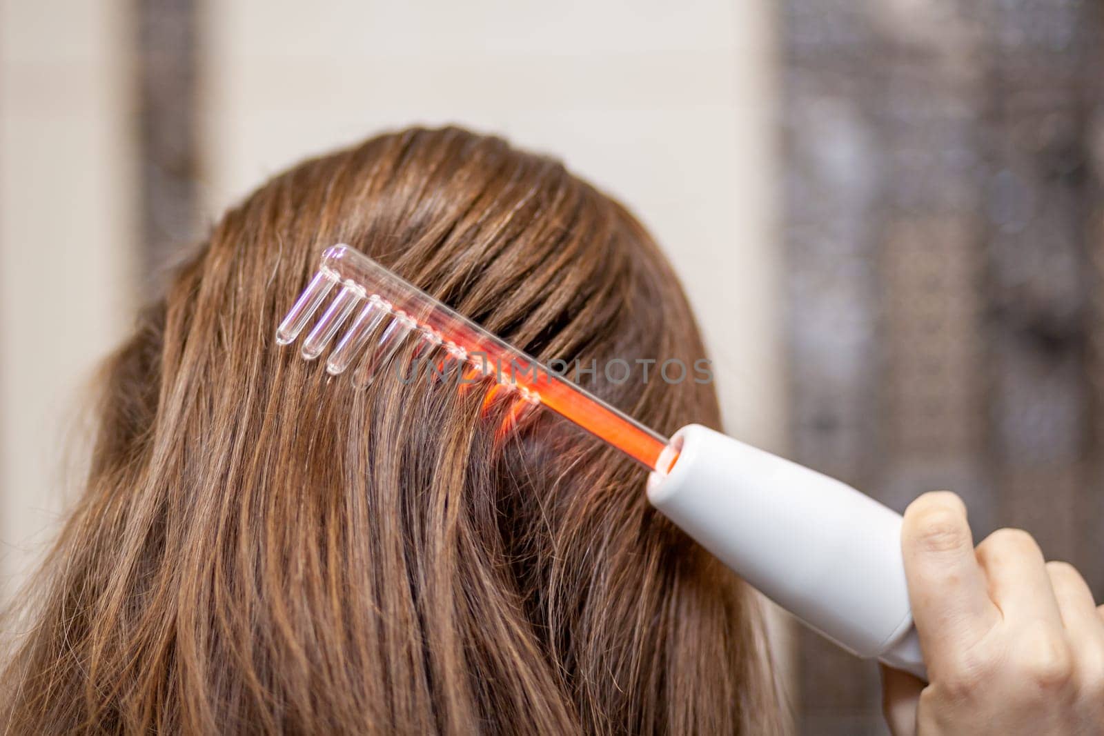 Woman uses darsonval for massage head's skin. by AnatoliiFoto