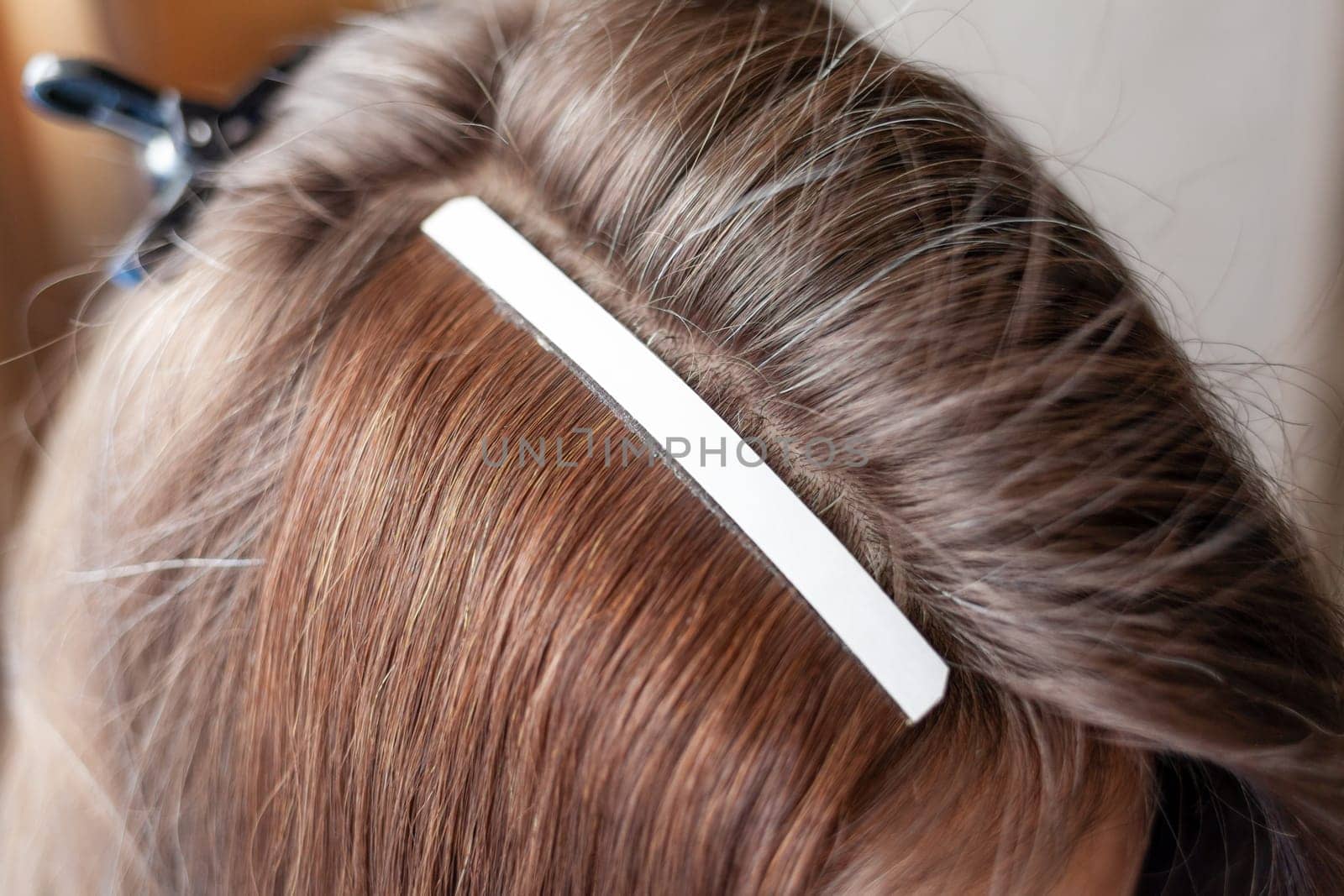 Hair ribbons for extensions on a woman's head at home. Hair extensions to thicken your own. Individual strands of hair close-up