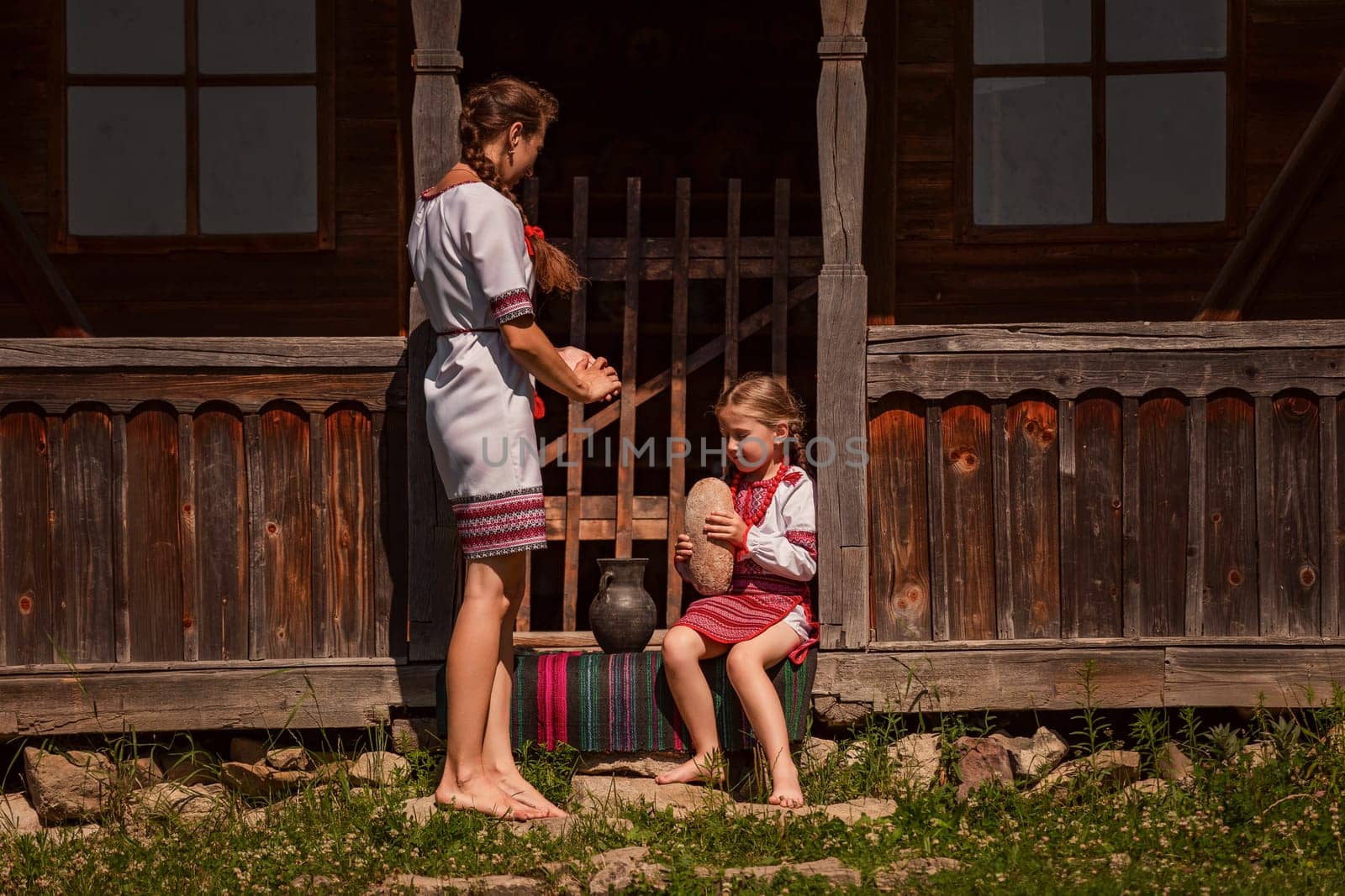 mother and daughter in Ukrainian folk dresses on the threshold of the house.