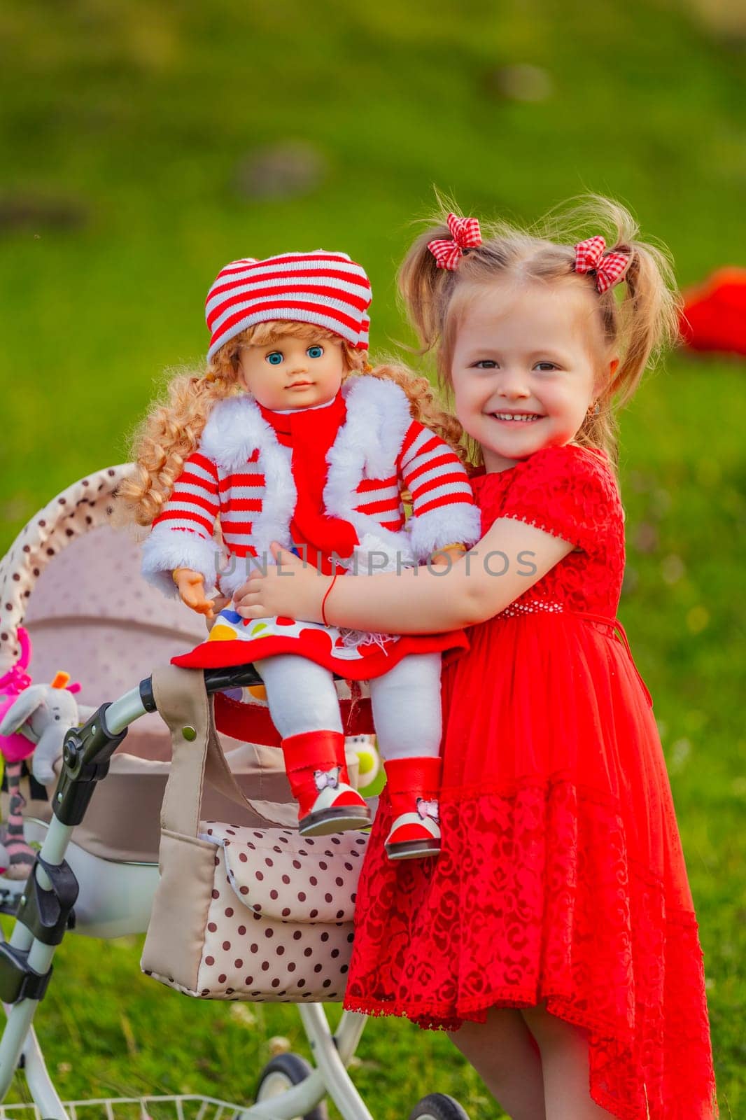 The girl plays with a doll in nature, holding her in her arms