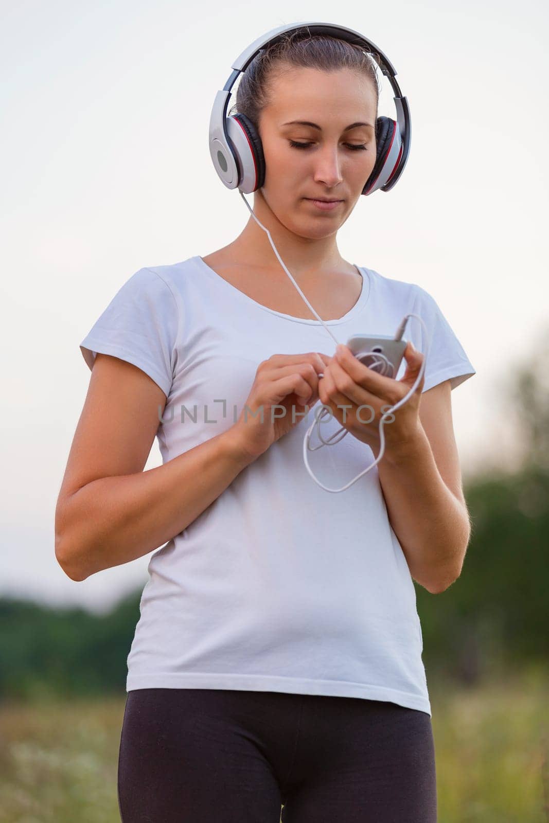 woman in headphones outdoors listening to music using phone