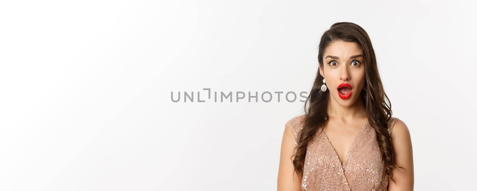 Image of attractive woman with red lips and hairstyle, wearing dress, staring surprised at camera, standing over white background by Benzoix