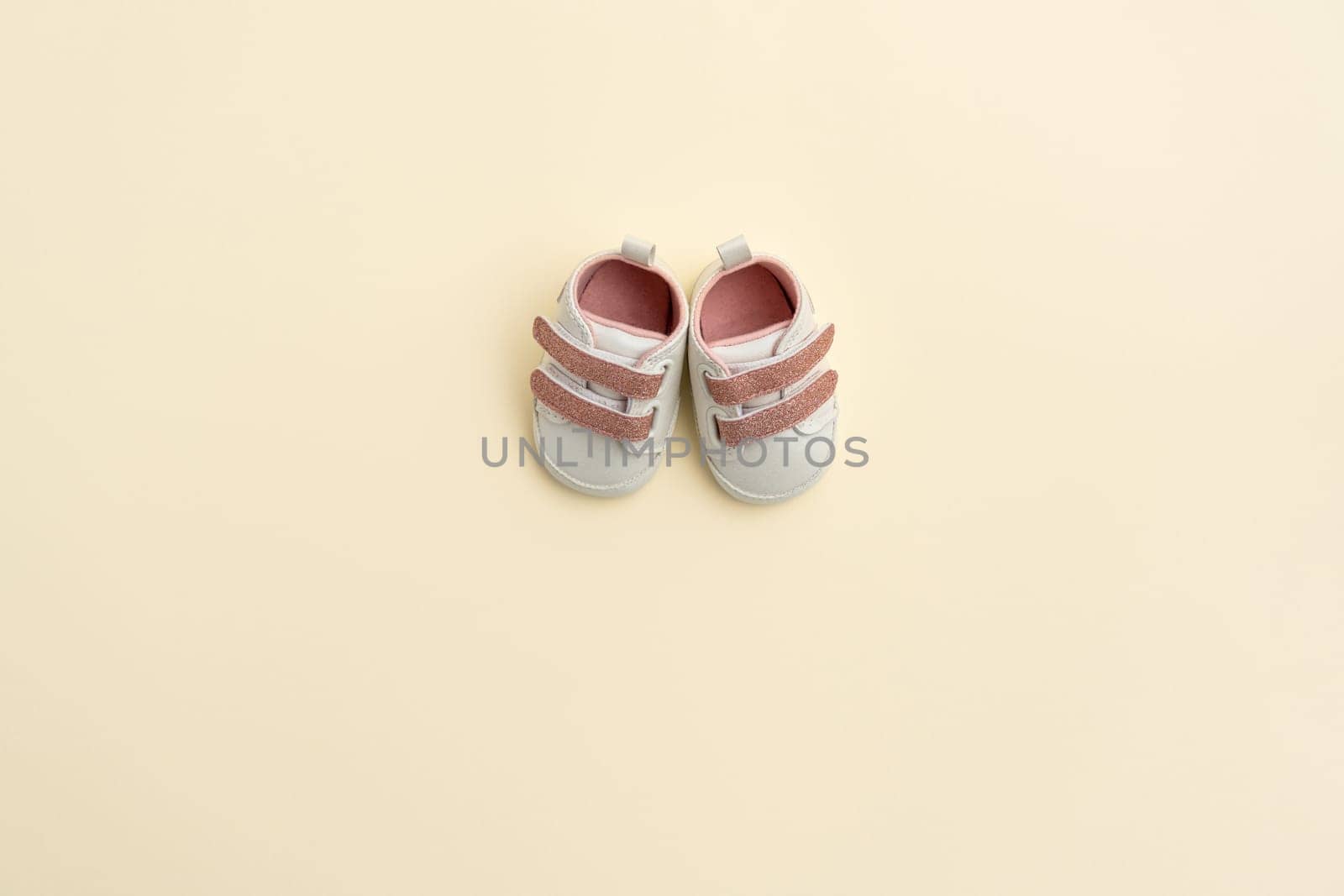 Baby pink shoes on yellow paper background with copy space. Baby clothes concept. Top view, flat by sdf_qwe