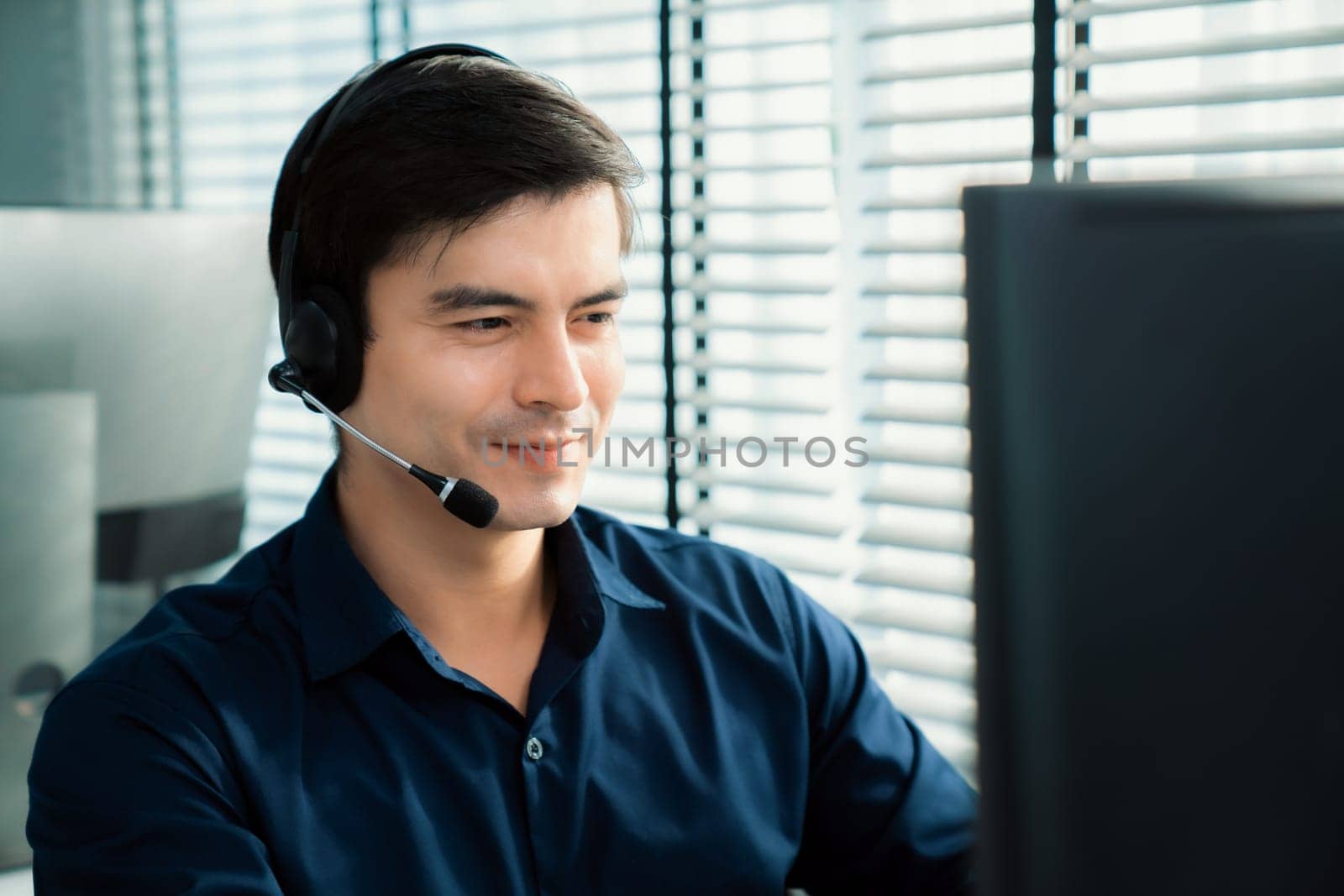 Young competent asian male call center agent working in the office. by biancoblue