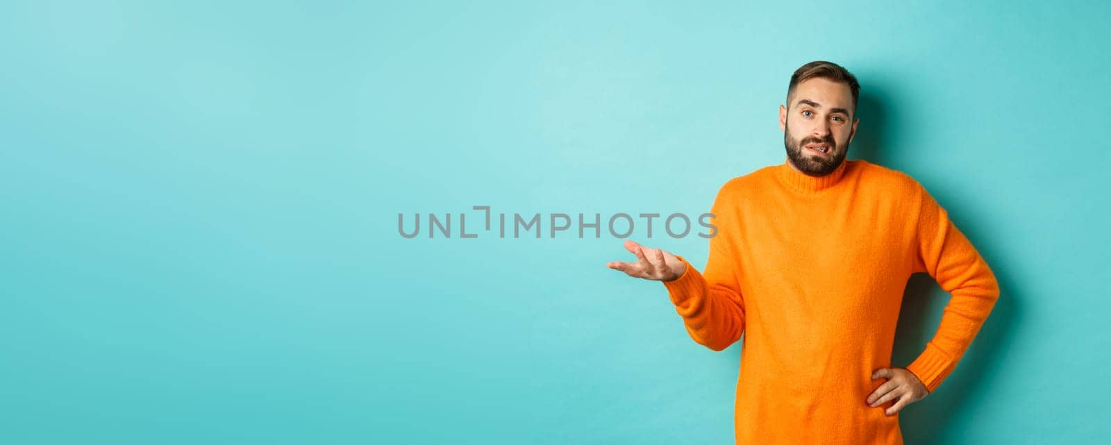 Careless and indifferent guy shrugging, looking unbothered, dont know anything, standing over light blue background.