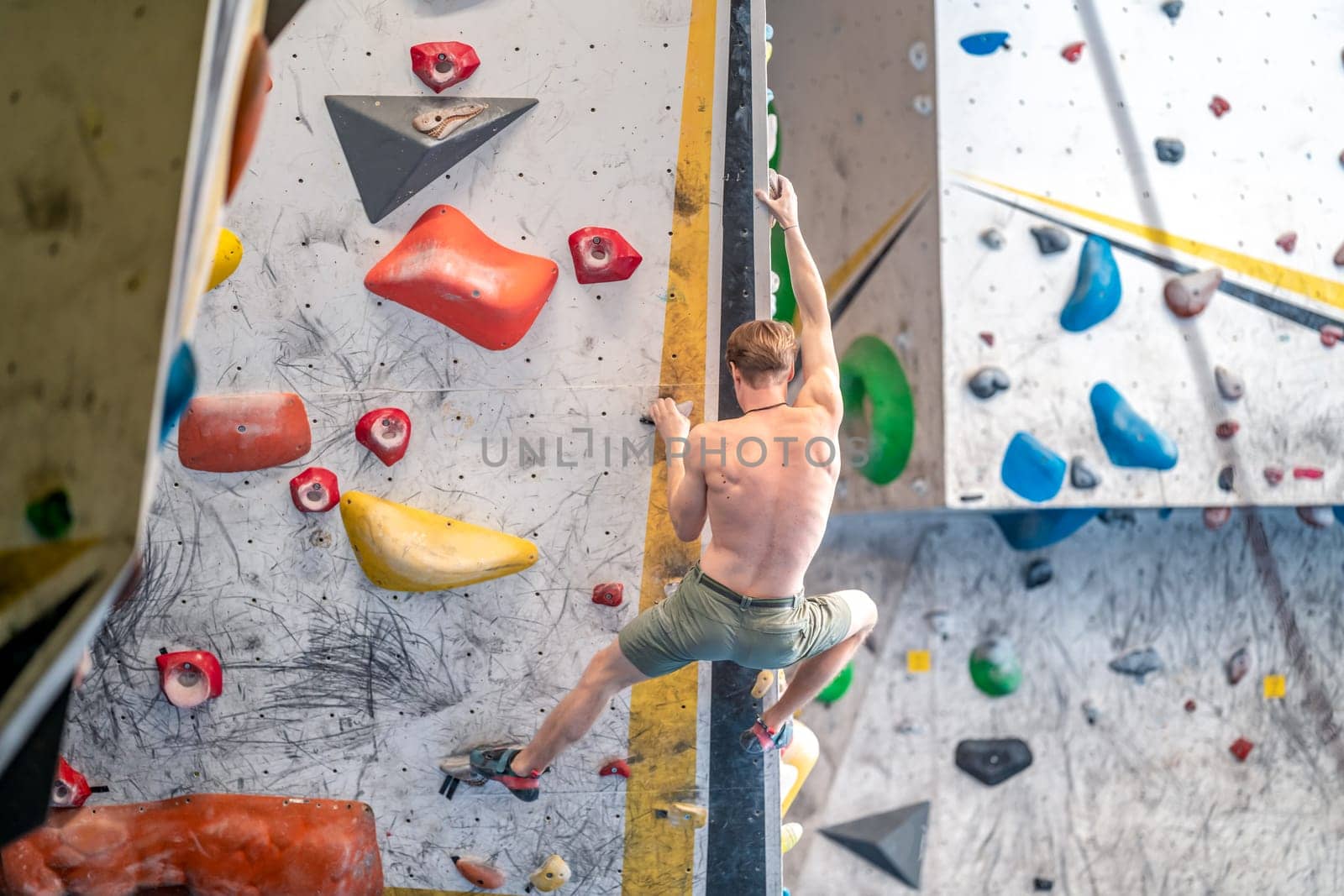 young man on a boulder climbing wall by Edophoto