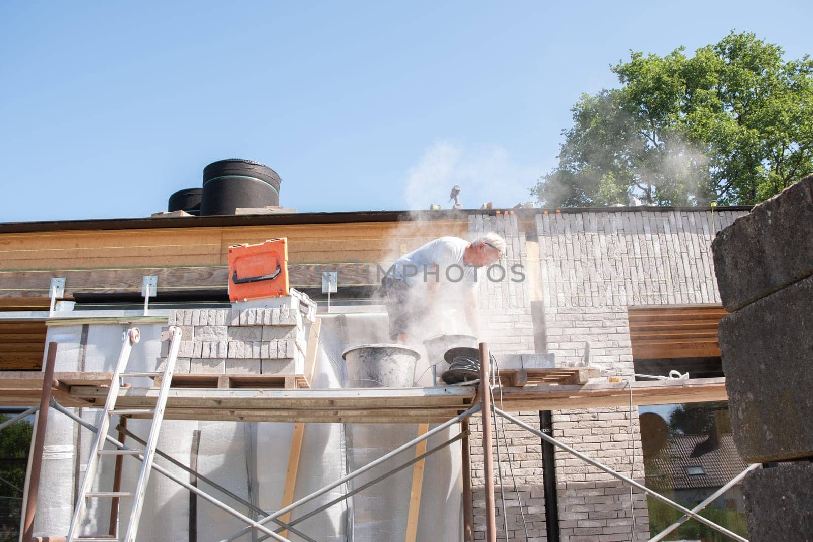 the bricklayer makes the facade of the house from gray bricks with cement and plaster at the construction site. High quality photo