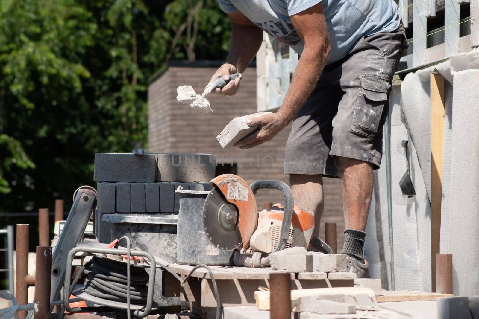 the bricklayer makes the facade of the house from gray bricks with cement and plaster at the construction site. High quality photo