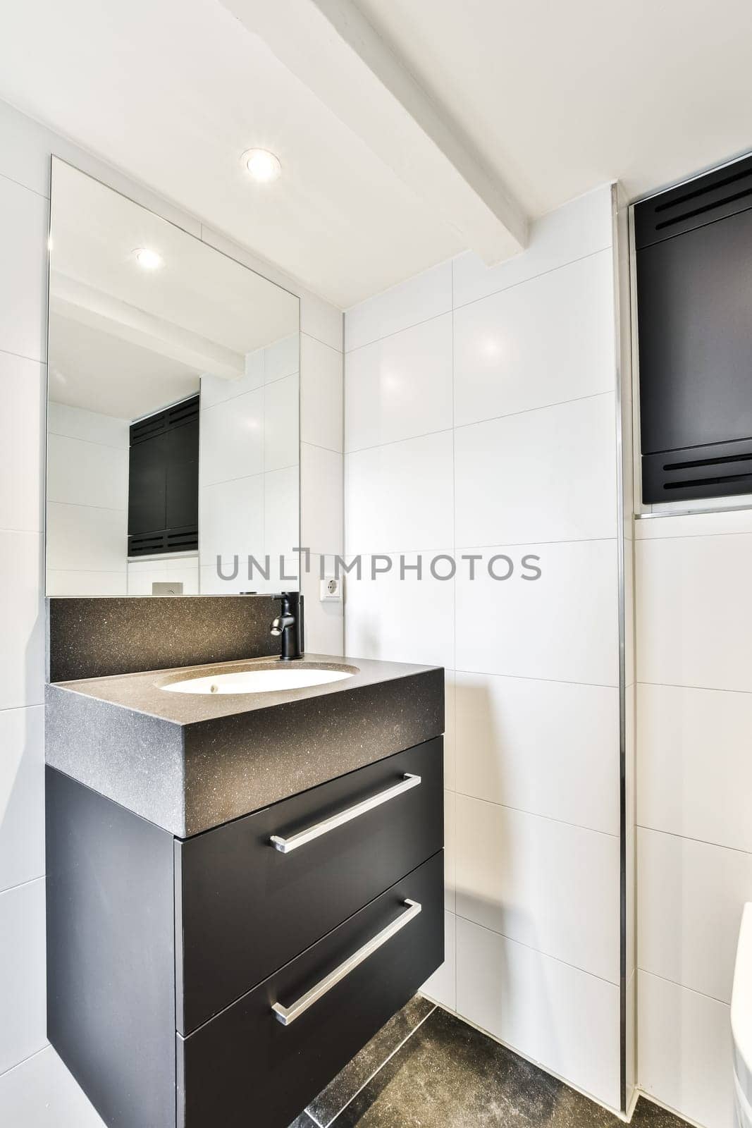 a black and white bathroom with a sink, mirror, and television on the wall in the corner of the room