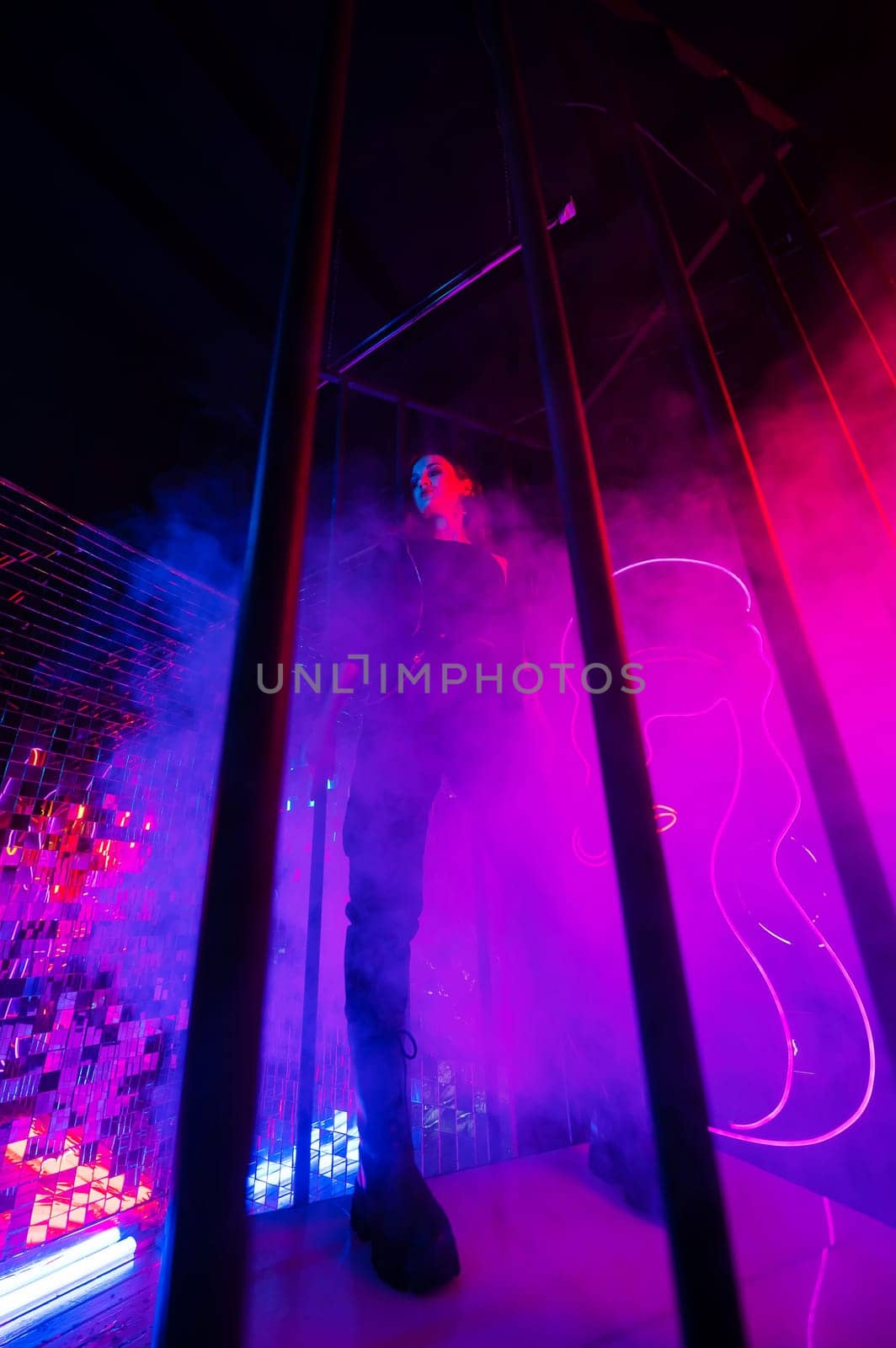 Caucasian woman in neon studio behind steel bars. by mrwed54