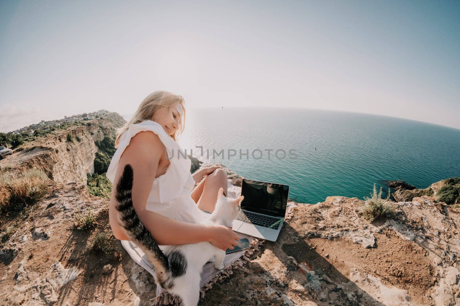 Woman sea laptop. Business woman in yellow hat working on laptop by sea. Close up on hands of pretty lady typing on computer outdoors summer day. Freelance, digital nomad, travel and holidays concept.