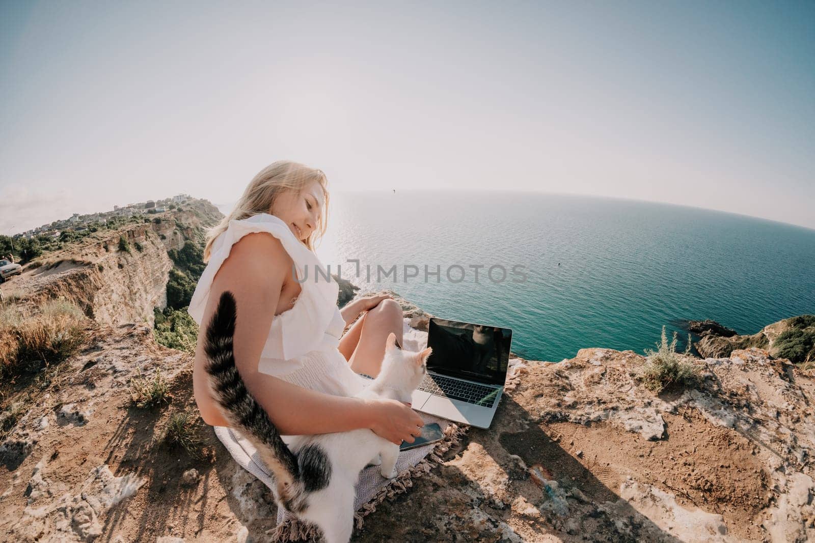 Woman sea laptop. Business woman in yellow hat working on laptop by sea. Close up on hands of pretty lady typing on computer outdoors summer day. Freelance, digital nomad, travel and holidays concept.