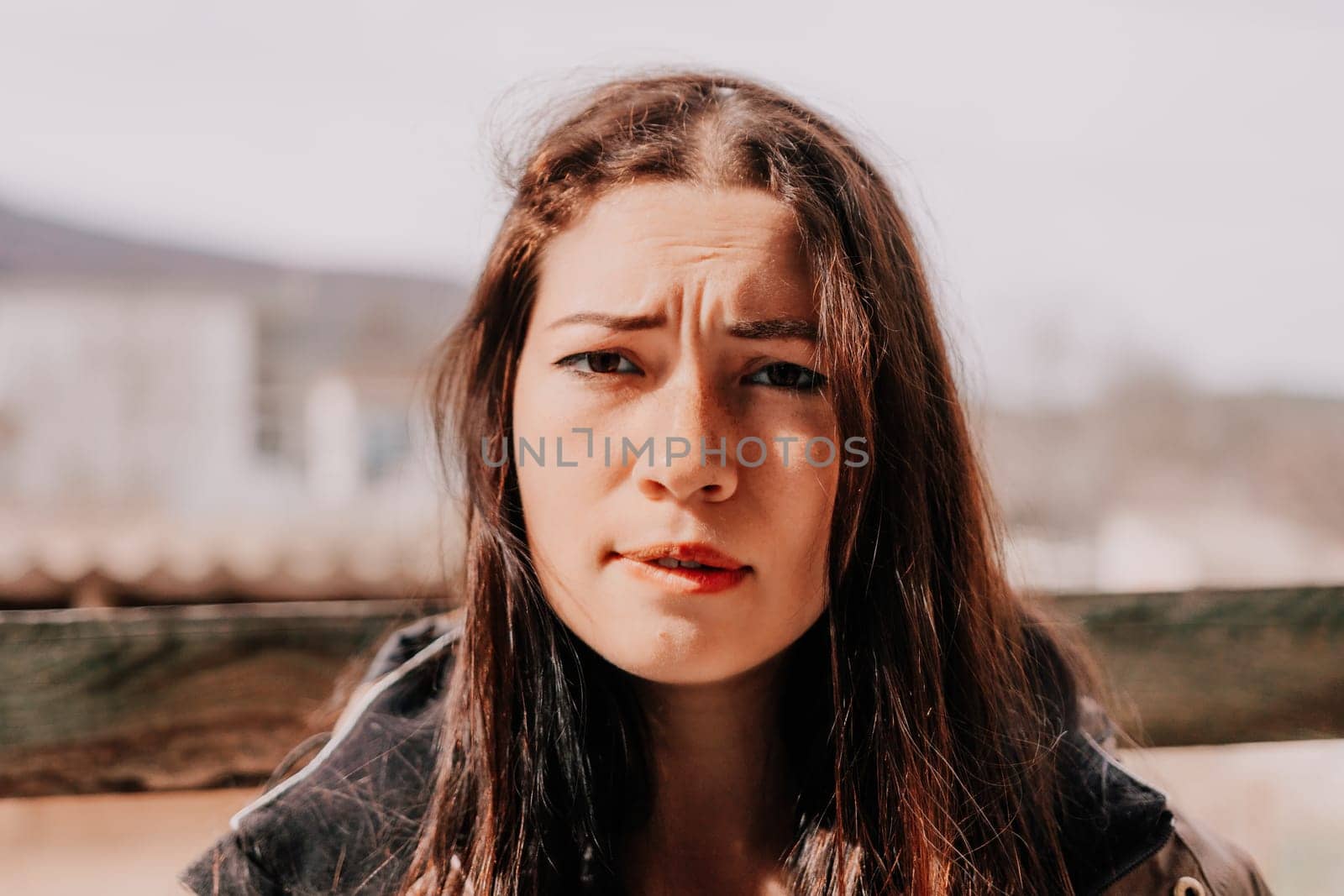 Happy young smiling woman with freckles outdoors portrait. Soft sunny colors. Outdoor close-up portrait of a young brunette woman and looking to the camera, posing against autumn nature background by panophotograph