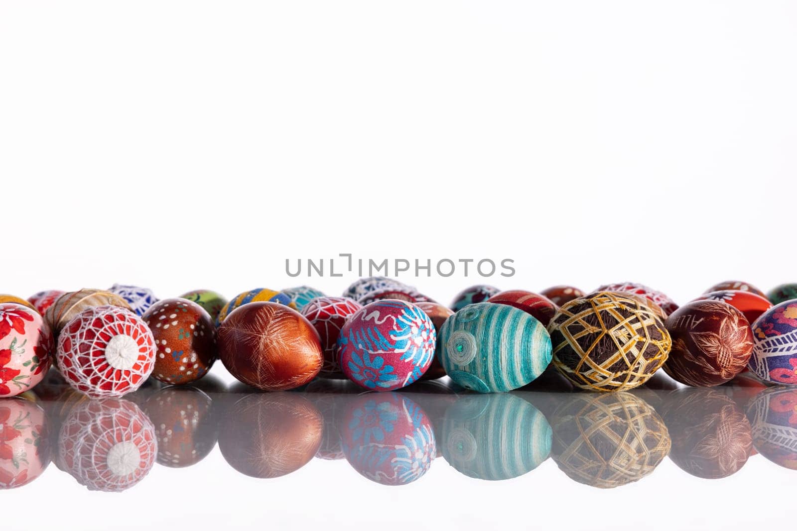 Composition of Easter eggs set in a row on a solid white background. The set Easter decoration is reflected in the glass.