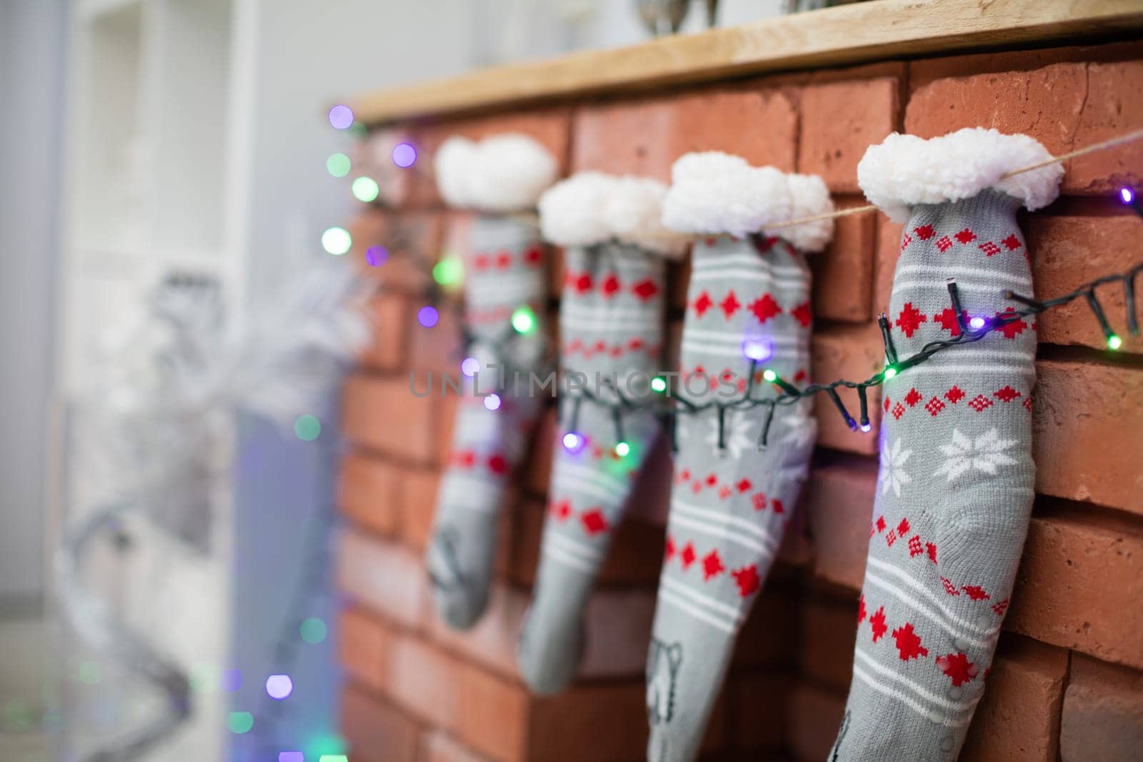Brick fireplace with Christmas socks and Christams lights. Warm woolen socks.