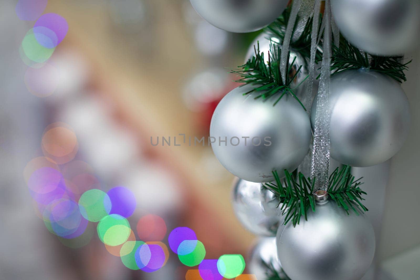 Silver baubles on spruce twigs and decorated fireplace in background.