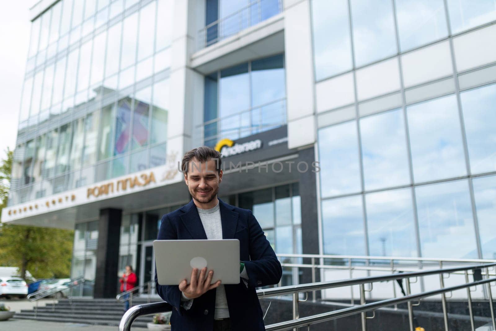 portrait of a caucasian male freelance designer with a laptop in his hands on the background of the building.