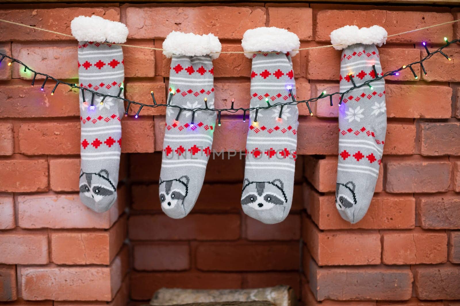 Christmas decoration on the fireplace with bricks of Christmas socks and Christmas tree lights.