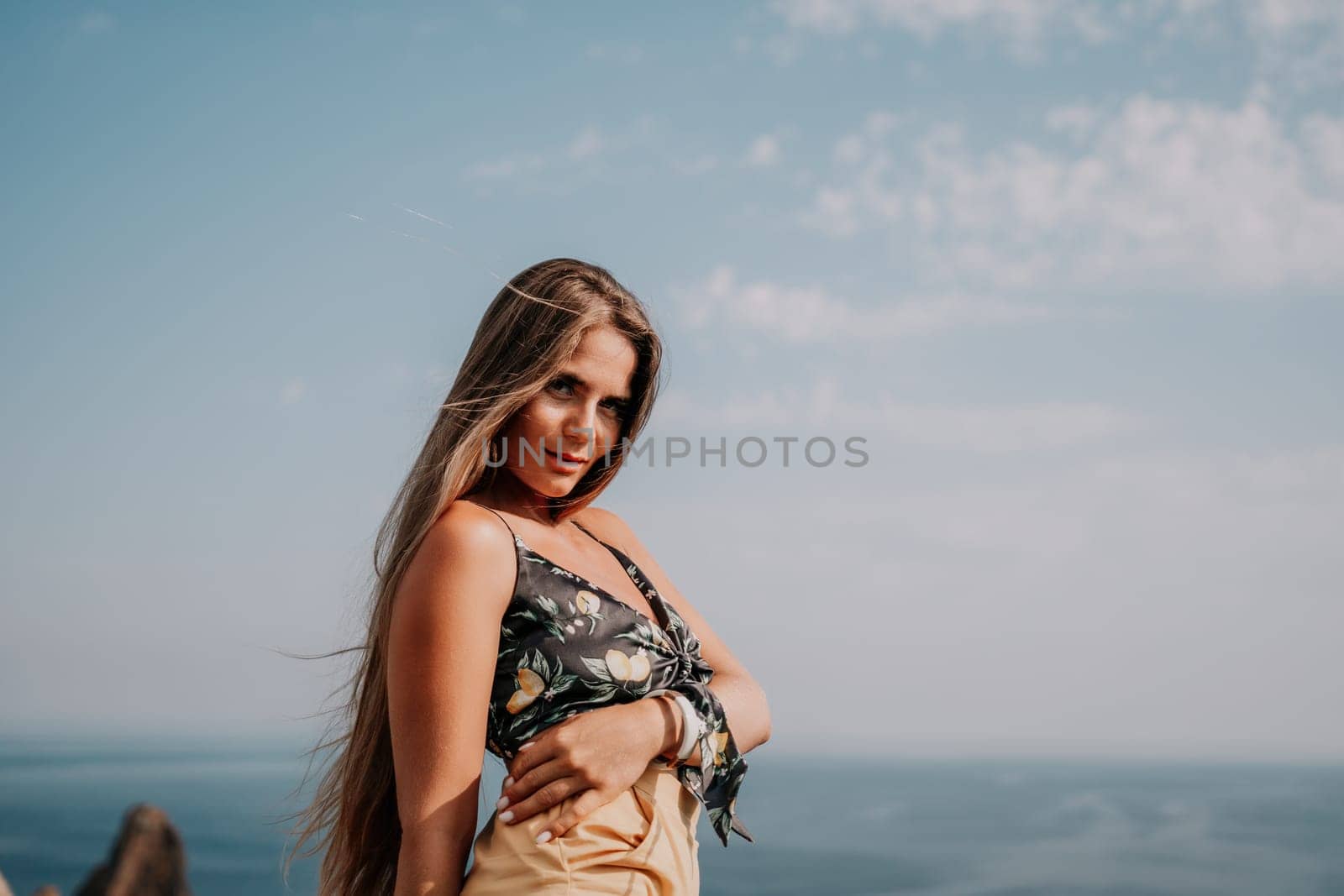 Woman travel sea. Happy tourist taking picture outdoors for memories. Woman traveler looks at the edge of the cliff on the sea bay of mountains, sharing travel adventure journey.