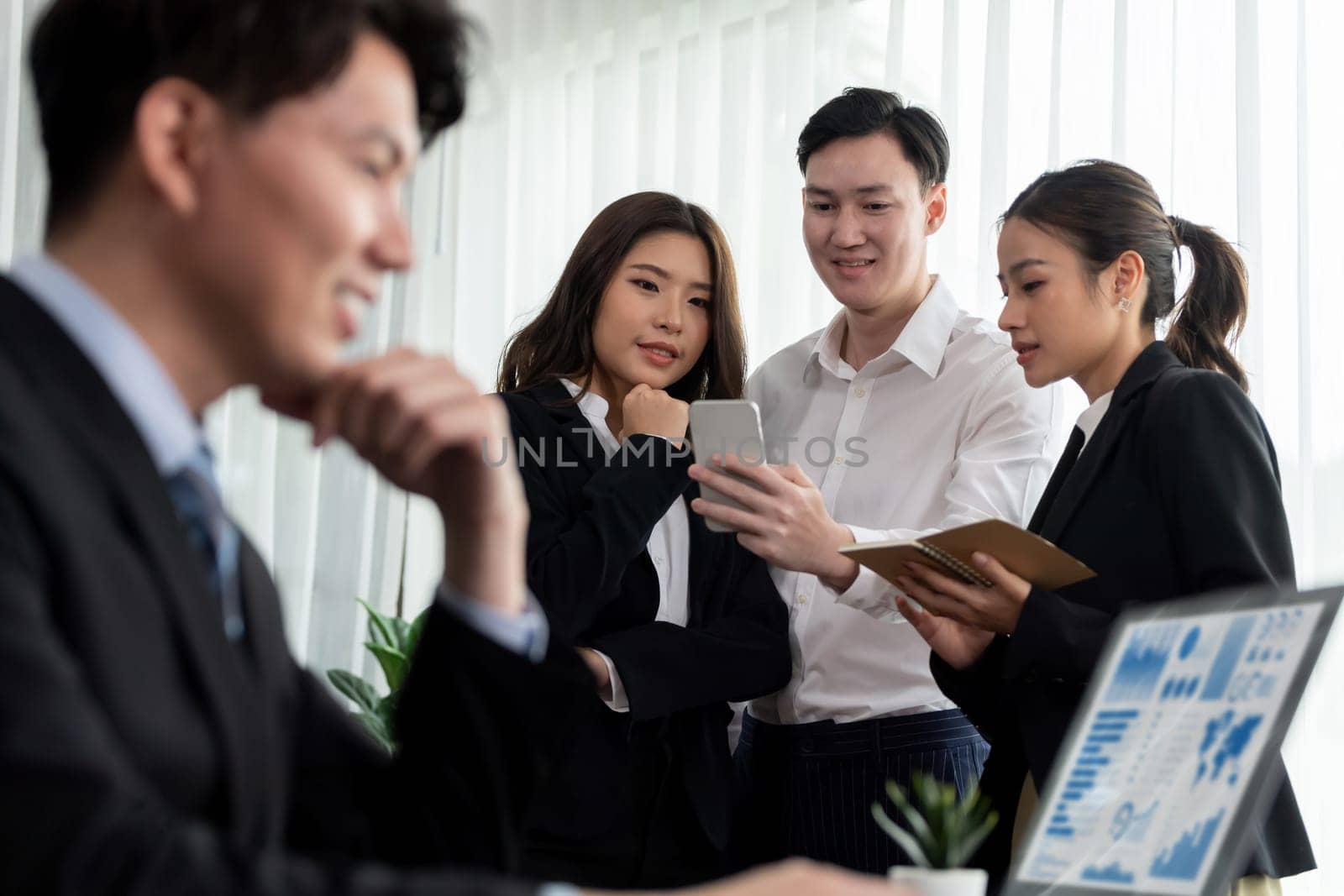Harmony in office concept as business people analyzing dashboard paper together in workplace. Young colleagues give ideas at manager desk for discussion or strategy planning about project.