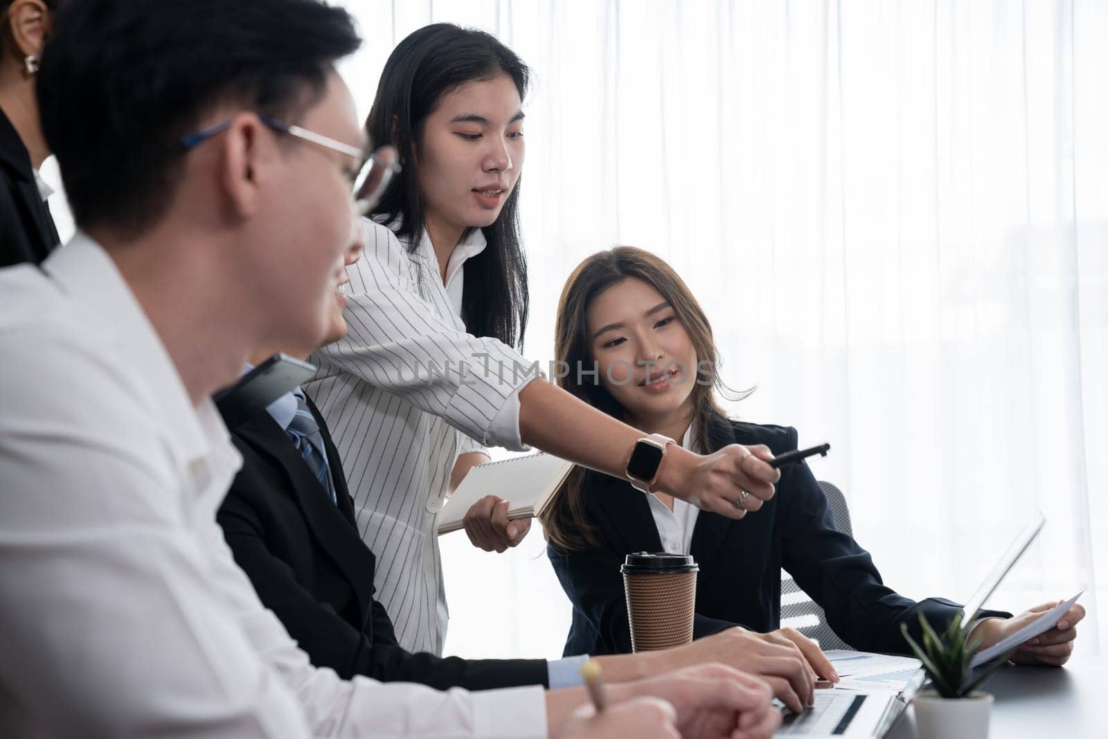 Harmony in office concept as business people analyzing dashboard paper together in workplace. Young colleagues give ideas at manager desk for discussion or strategy planning about project.