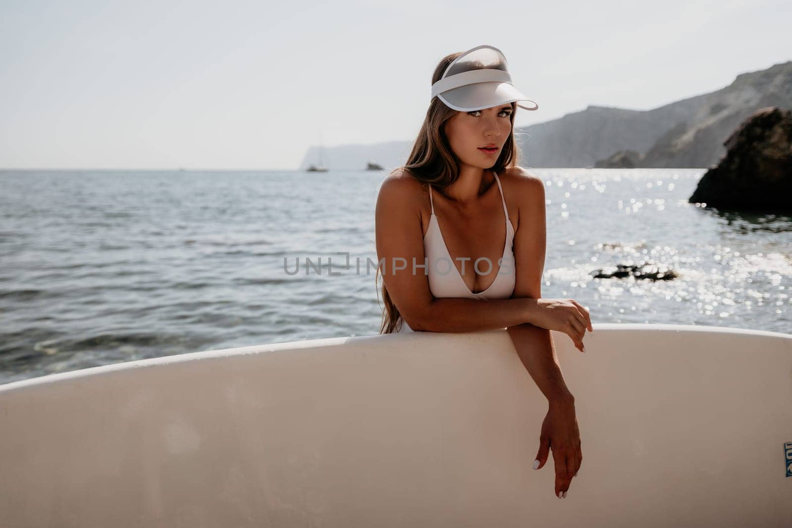 Woman sea sup. Close up portrait of happy young caucasian woman with long hair looking at camera and smiling. Cute woman portrait in a white bikini posing on sup board in the sea by panophotograph