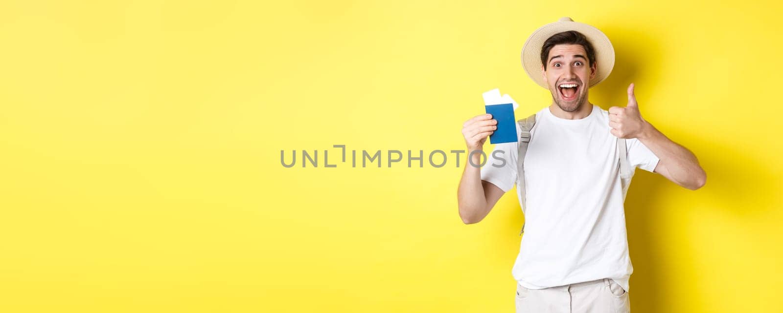 Tourism and vacation. Satisfied male tourist showing passport with tickets and thumb up, recommending travel company, standing over yellow background.