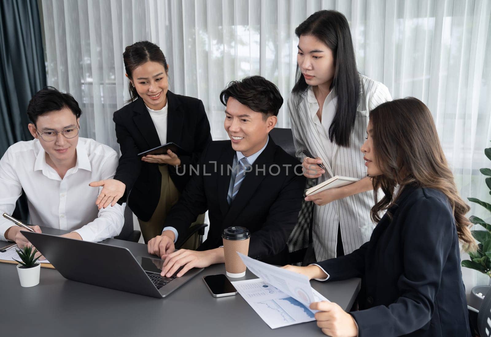 Harmony in office concept as business people analyzing dashboard paper together in workplace. Young colleagues give ideas at manager desk for discussion or strategy planning about project.