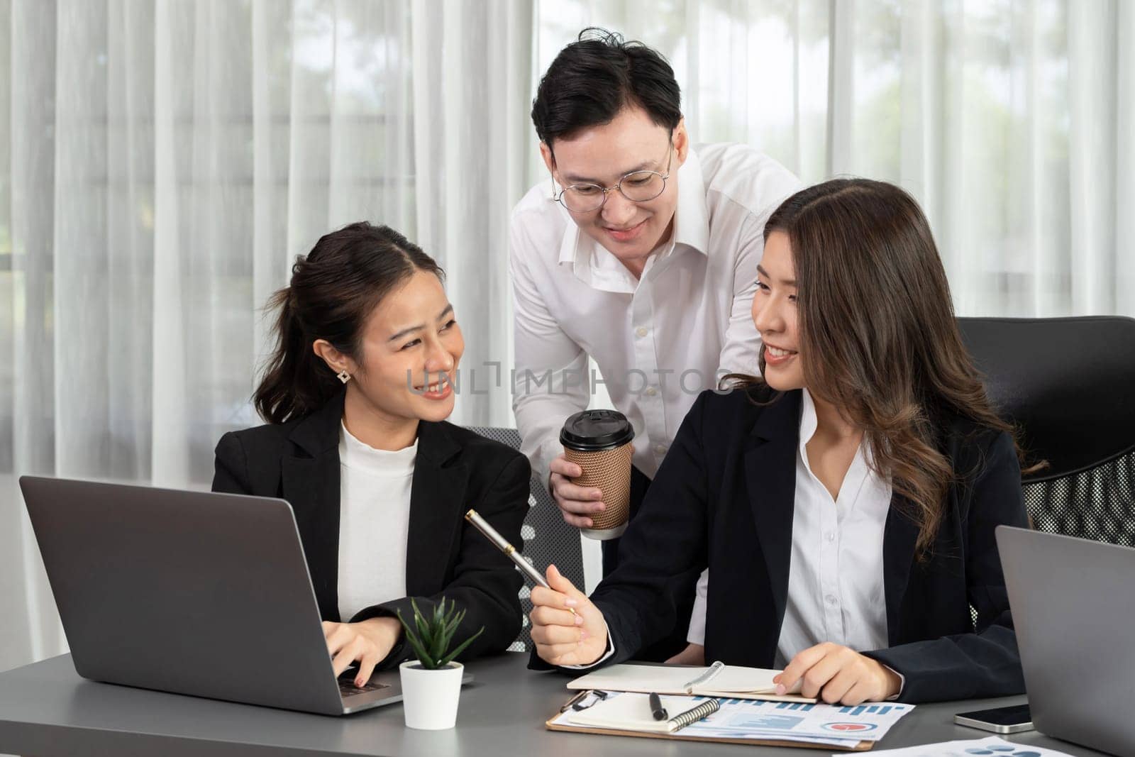 Harmony in office concept as business people analyzing dashboard paper together in workplace. Young colleagues give ideas at manager desk for discussion or strategy planning about project.