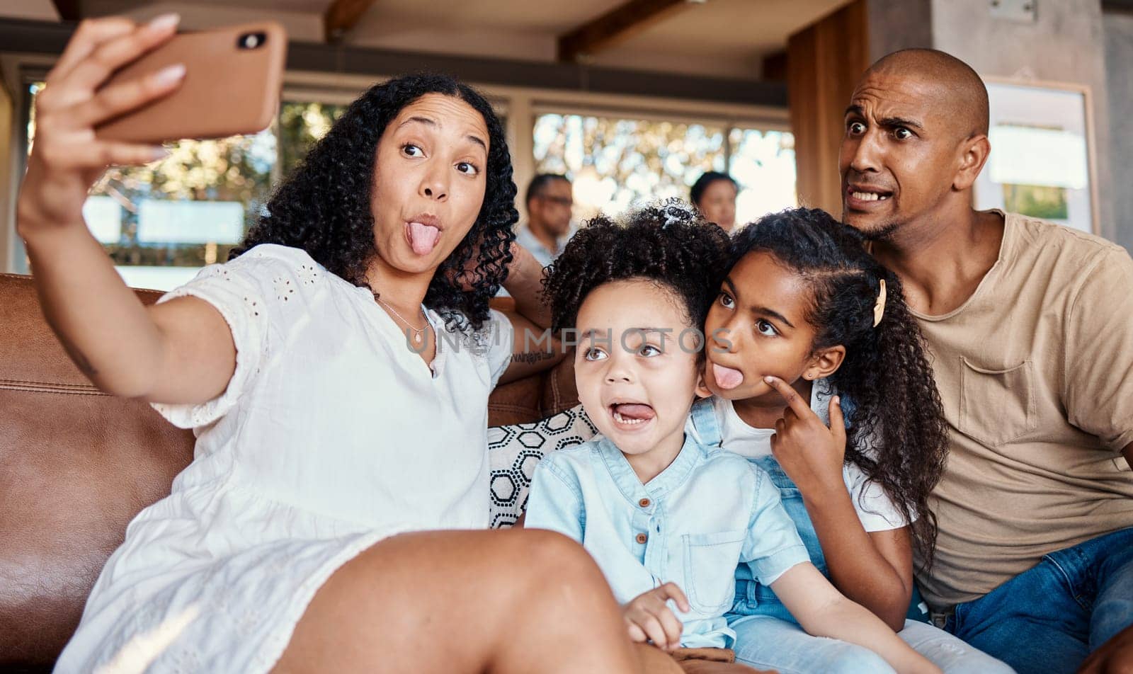 Family, funny face and selfie with tongue out in home, having fun and bonding together. Interracial, comic photography and father, mother and girls taking pictures for social media and happy memory