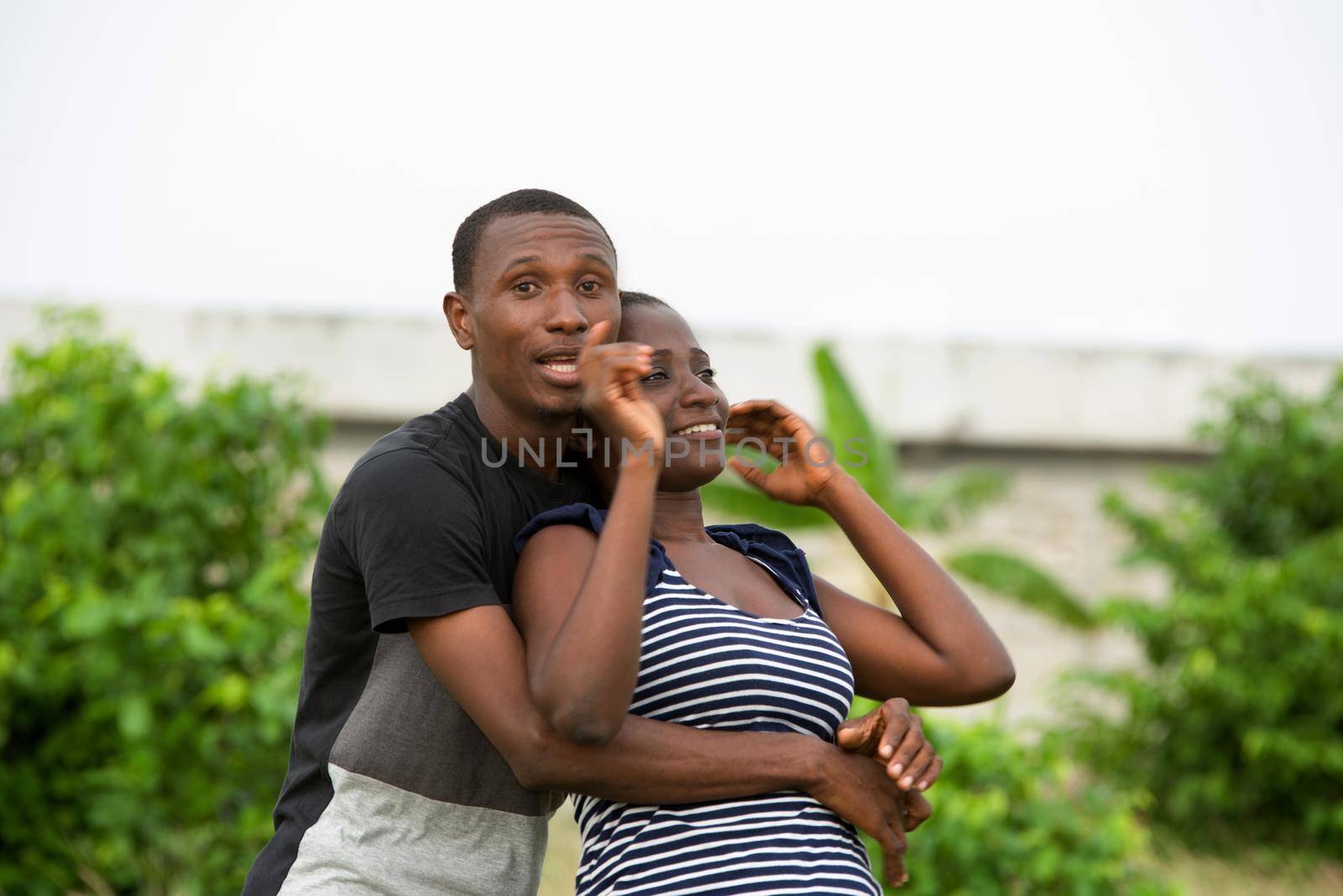 cheerful young couple hugging standing at the park in the middle of the day