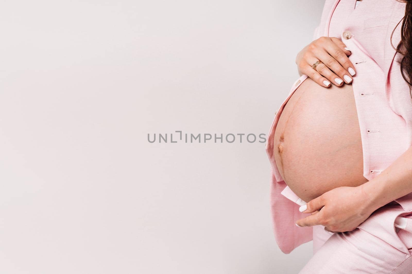 pregnant woman in a suit close-up on a gray background.