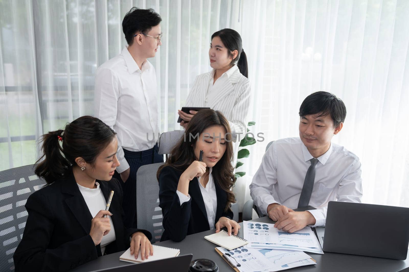 Harmony in office concept as business people analyzing dashboard paper together in workplace. Young colleagues give ideas at manager desk for discussion or strategy planning about project.