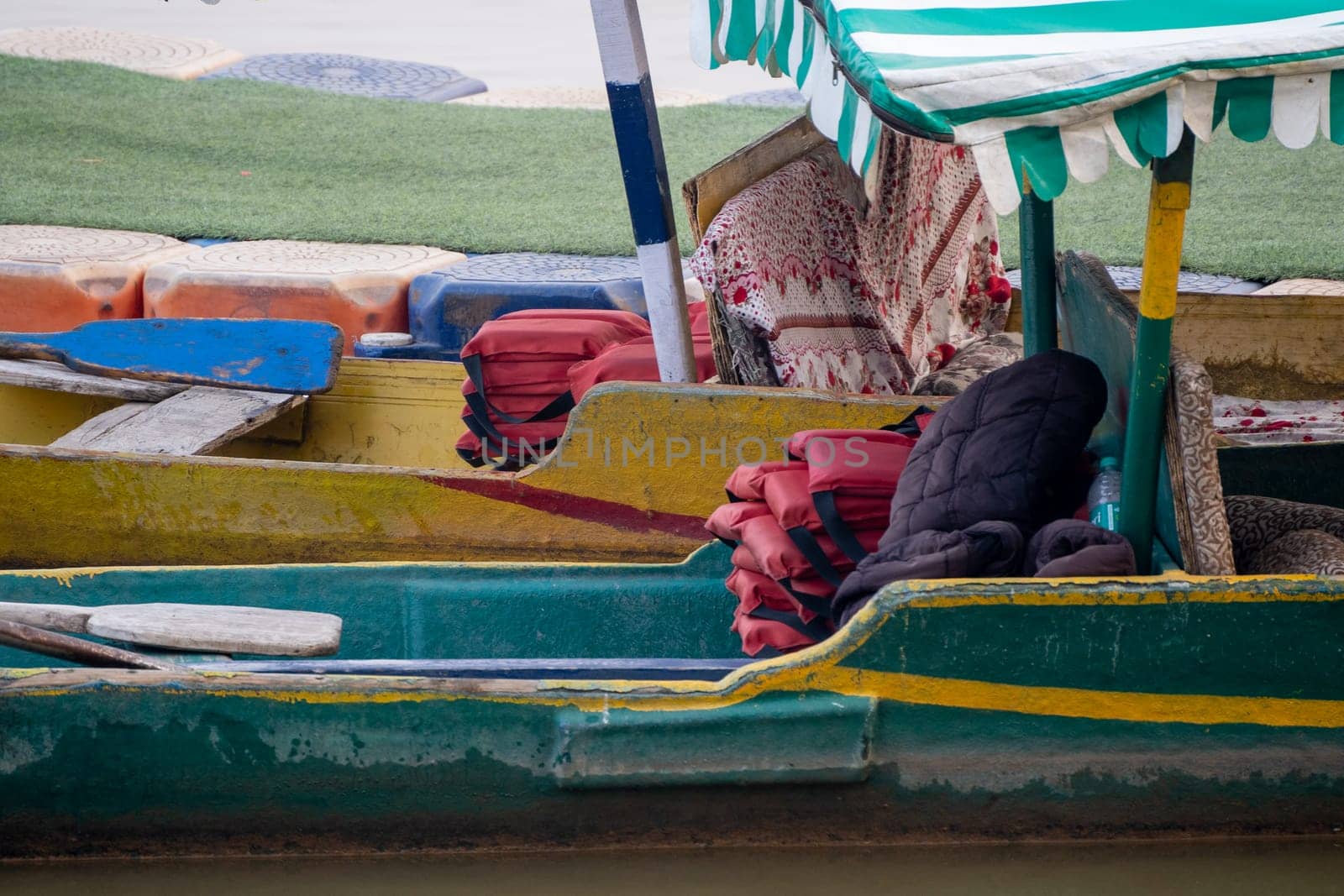 life jackets and cushions placed in shaded boat for tourists to ride on sukhna lake in chandigarh in summers by Shalinimathur